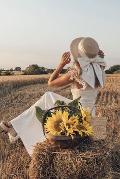 a woman sitting in the middle of a field with sunflowers on her lap