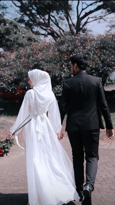 a bride and groom walking down the street holding hands