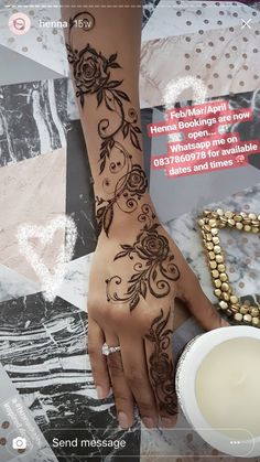 a woman's hand with henna tattoos on it and a candle next to her