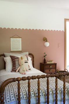 a bed room with a neatly made bed and a teddy bear sitting on the pillow