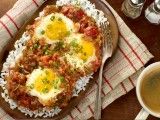 two fried eggs are on top of rice next to a cup of tea and spoon