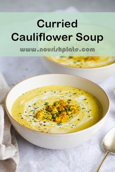 two white bowls filled with soup on top of a table next to silver spoons