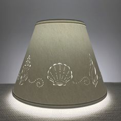 a lamp shade with shells and seaweeds on the bottom, lit up at night