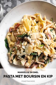 a white bowl filled with pasta covered in meat and cheese on top of a table