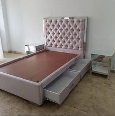 a bed with pink upholstered headboard and drawers on the bottom, next to a mirrored side table