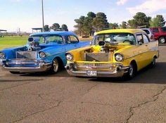 two old cars parked in a parking lot with other classic cars behind them on the pavement