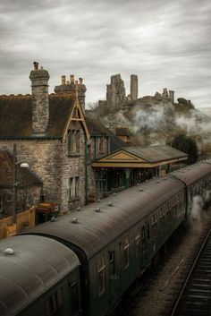 a train traveling down tracks next to a tall building