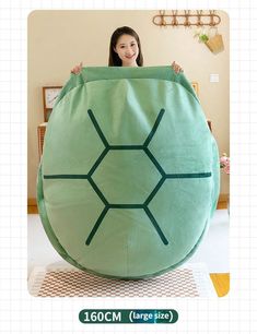 a woman is holding up a large green turtle shaped cushion in front of her face