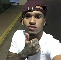 a man with tattoos on his arm and hand pointing to the side while wearing a hat