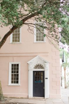 a pink house with white trim and windows on the front door is seen in this image