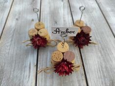 some wine corks and flowers are hanging from hooks on a wooden table with a name tag