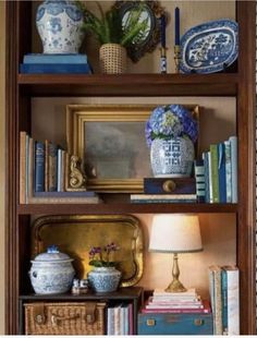 a bookshelf filled with lots of books and vases on top of it