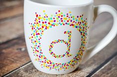 a white coffee cup with multicolored dots and the number five on it's side