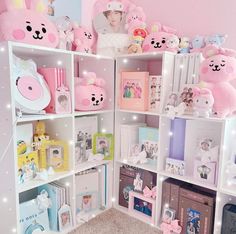 a room filled with lots of stuffed animals on top of white shelving units covered in lights