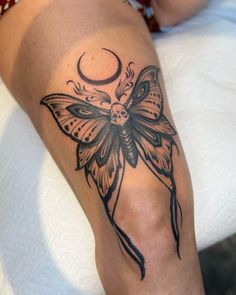 a woman with a butterfly tattoo on her leg and the moon in the sky behind her