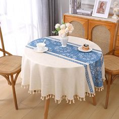 a dining room table with a blue and white table cloth on it, next to two chairs