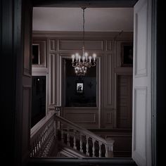 a chandelier hanging from the ceiling in a room with white walls and stairs