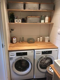 a washer and dryer in a small room with open shelving on the wall