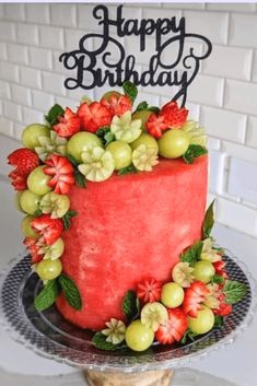 a birthday cake decorated with fruit and flowers