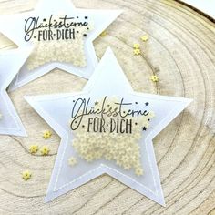 three white stars with black writing on them sitting on top of a piece of wood