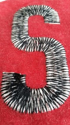 the letter s is made up of black and white stripes on a red fabric background