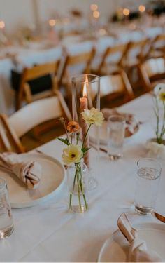 the table is set with white linens, silverware and flowers in vases