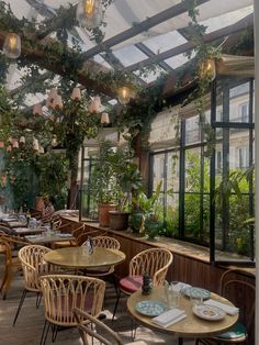 an indoor restaurant with tables and chairs covered in plants