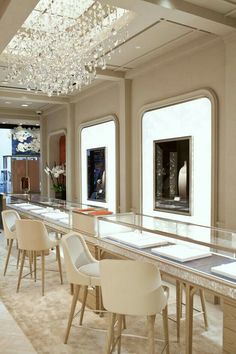 an elegant dining room with chandelier and marble counter tops, along with white chairs