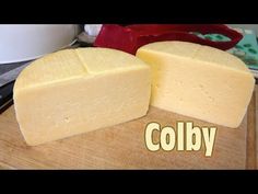 two pieces of cheese sitting on top of a cutting board with the word colby next to it