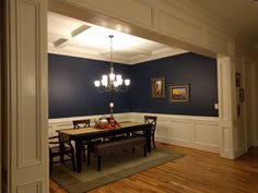 an empty dining room with blue walls and wood flooring is seen in this image