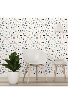 two white chairs sitting next to a potted plant on top of a wooden floor