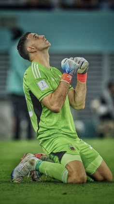 a soccer player sitting on the ground with his head up and hands in the air