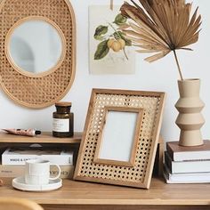 a wooden table topped with two framed pictures next to a vase filled with flowers and plants