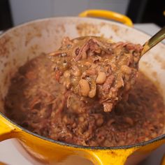 a spoon full of beans and meat in a pot