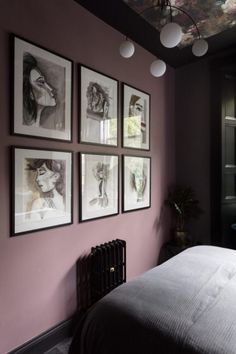 a bedroom with pink walls and pictures on the wall above the bed, along with an iron radiator