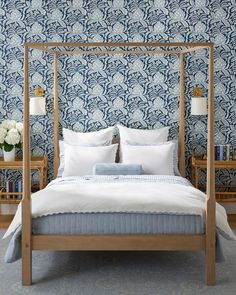 a bedroom with blue and white wallpaper and a four poster bed in the middle