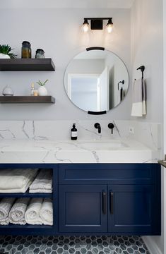 a bathroom with marble counter tops and blue cabinets, along with white towels on shelves