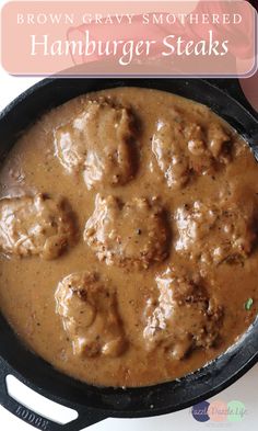 a skillet filled with meatballs and gravy on top of a table