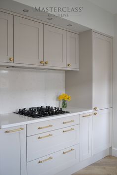 a kitchen with white cabinets and yellow flowers on the stove top in front of it