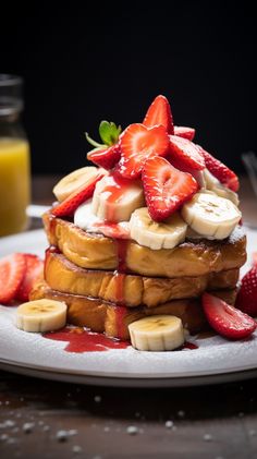 a stack of french toast topped with sliced bananas and strawberries on a white plate