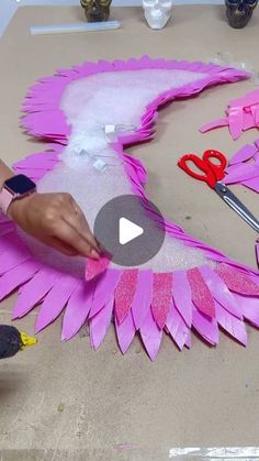 a person cutting out pink paper with scissors