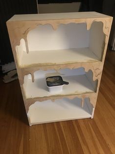 a white shelf with a hat on it in the middle of a wooden floored room