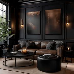 a living room with black walls, leather furniture and candles on the coffee table in front of it