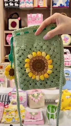 a hand holding a green crocheted bag with yellow flowers on the front and bottom