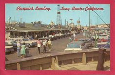 an old postcard shows people walking on the sidewalk in front of shops and cars