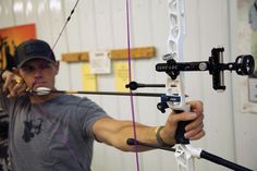 the man is practicing his archery skills with an arrow and bow aiming device in front of him