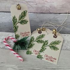 two christmas gift tags sitting next to a candy cane