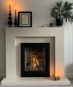 a fire place with candles and pictures on the wall