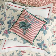 a bed topped with lots of pillows covered in red and white sheets