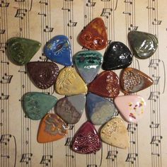 a bunch of different colored guitar picks sitting on top of sheet music